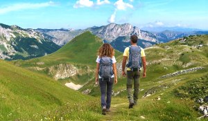 Muškarac i žena obučeni u BB outdoor odjeću planinare Zelengorom i uživaju u predivnoj planinskoj panorami koja se pruža ispred njih.